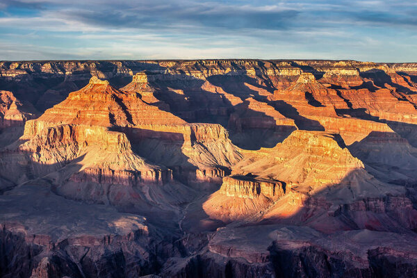 Majestic rock formations and deep canyons display vibrant colors in the afternoon light at Grand Canyon in Arizona.