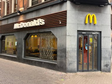 Hollanda, den haag - 18 Ekim 2024: Lahey 'de bir caddede bir McDonalds restoranı bulunmaktadır. Gösterişli dış görünüş, müşterileri hareketli bölgede yemek yemeye davet eden önemli bir logoya sahip..