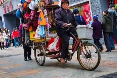 Chengdu, Çin - 29 Kasım 2009: Bir kurye, Chengdu Çin 'deki işlek bir caddede çeşitli mallarla dolu bir bisiklet sürüyor..
