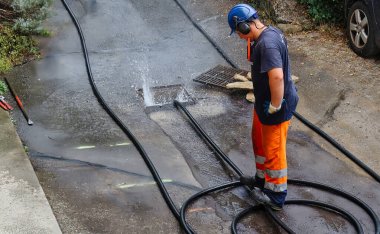 Menthon Saint Bernard, Fransa - 09 Eylül 2021: profesyonel bir işçi kanalizasyon borusunu temizlerken pompalı araba ve yüksek basınçlı hortumla meşgul