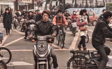 Chengdu, Çin - 27 Kasım 2009: Motosiklet ya da scooter kullanan biri kalabalık bir caddede araba kullanıyor