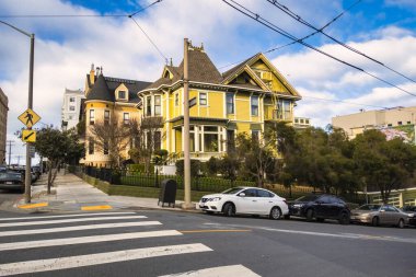 San Francisco, ABD - 14 Şubat 2020: Viktorya dönemi evleri dik tepeler ve kavşakta park etmiş arabalarla tipik bir San Francisco caddesi