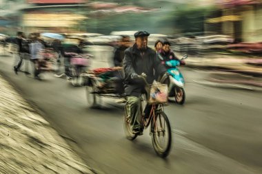 Chengdu, Çin - 27 Kasım 2009: Chengdu 'da hareketli bir cadde Çin' de kentsel yaşamı gösteren bulutlu bir gökyüzü altında bisikletçiler ve motorsikletler yer alıyor.