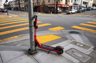 San Francisco, ABD - 14 Şubat 2020: Kırmızı bir Uber kiralık scooter, Şubat 2020 'de San Francisco kaldırımında bir direğe park edilmiştir..