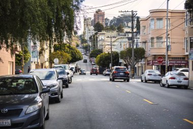 San Francisco, ABD - 14 Şubat 2020: Tipik bir San Francisco sokağı Viktorya dönemi evleri ve yan tarafında park etmiş arabaların bulunduğu dik bir tepeye sahiptir.