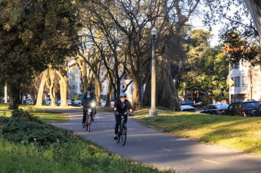 San Francisco, ABD - 12 Şubat 2020: San Francisco Panhandle 'da bir bisiklet yolu boyunca bisikletliler Şubat 2020 sabahı kask takarak bisiklet sürüyorlar.