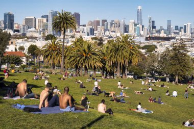 San Francisco, Amerika Birleşik Devletleri - 12 Şubat 2020: Dolores Park 'ta yarı çıplak haldeki insan grupları güneşin ve San Franciscos ufuk çizgisinin tadını çıkarıyor