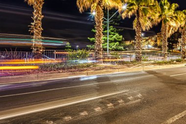 Bondi Plajı, Avustralya - 20 Ekim 2009: Canlı bir gecede Bondi Sydney 'de palmiye ağaçlarının yanından geçen araçlar yol boyunca renkli ışıklar yanar.