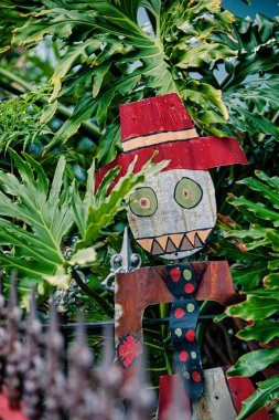 Melbourne, Avustralya - 08 Ekim 2009: Victoria Avustralya 'da bir bahçe ortamındaki yemyeşil yaprakların arasında kırmızı şapkalı canlı bir korkuluk duruyor.