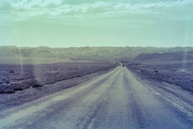 Almaty, Kazakistan - 16 Haziran 2017: Almaty Kazakistan 'daki açık gökyüzü ve uzak tepelerle dağlık arazide uzanan uzun yol.