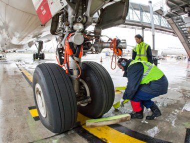 Paris, Fransa - 26 Nisan 2012: Yer ekibi öğle saatlerinde bir havaalanında kalkış için uçak hazırlarken uçak lastiklerini denetliyor.