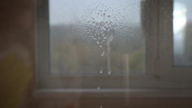 Eldivenli kadın elleri pencereyi sprey sıvıyla yıkıyor. Ev hanımı ev işi yapar. Şeffaf parlak camları tozdan temizlemek.