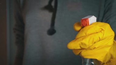 Eldivenli kadın elleri pencereyi sprey sıvıyla yıkıyor. Ev hanımı ev işi yapar. Şeffaf parlak camları tozdan temizlemek.