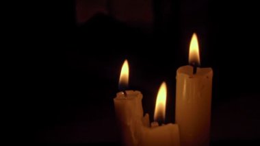 Siyah arka planda sarı renkli beyaz parafin mumlar. Bir mum hareketsiz yanar ve ateş yayar..