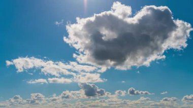 Beyaz kabarık bulutlar mavi gündüz vakti gökyüzünde yavaşça süzülür. Güzel gökyüzü hareket ediyor. Kar beyazı bulutlar yana doğru hareket ediyor..