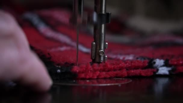ミシンの針と足が布の近くに浸透します 眼鏡をかけた老女が古いミシンで縫う 縫い目は赤い生地の上に機械製の縫い代を作る — ストック動画