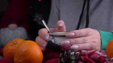 Girl drinks coffee in cozy New Years atmosphere on background of Christmas tree. New Years Eve alone beautiful girl. The aroma of coffee in a warm cozy blanket.