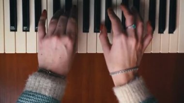 Female hands with fingers play the piano keyboard close-up top view. The piano keys are black and white. Musical instrument, spiritual education, calm music.