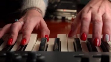 Female hands with fingers play the piano keyboard close-up front view. The piano keys are black and white. Musical instrument, spiritual education, calm music.