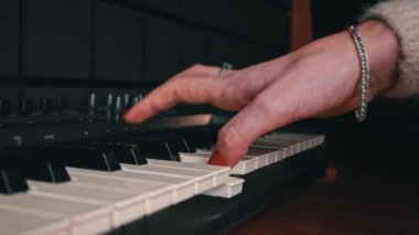Female hands with fingers play the piano keyboard close-up side view. The piano keys are black and white. Musical instrument, spiritual education, calm music.
