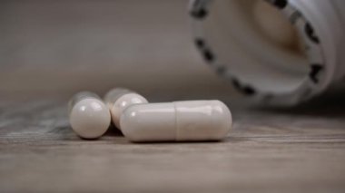 Beyaz hap kapsülleri yavaş çekimde yüzeye çıkar. İlaç kapsülleri. Sağlık hizmetleri ve ilaç üretimi kavramı. Kendimi kötü hissediyorum, hastane..