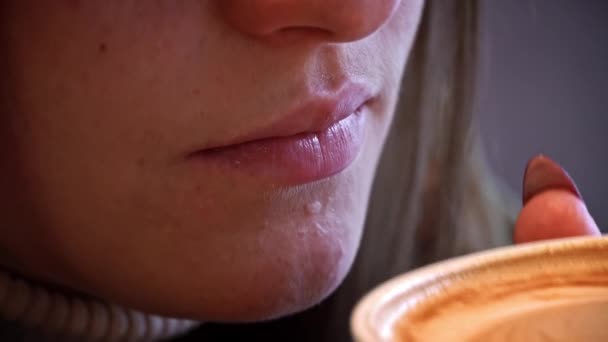 여자가 클로즈업으로 커피를 마십니다 뜨거운 카푸치노를 입술로 옵니다 소녀가 커피숍에서 — 비디오