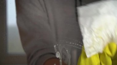 Womens hands in gloves wash the window with a spray liquid slow mo. Housewife does housework. Cleaning transparent shiny glass from dust.
