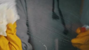 Womens hands in gloves wash the window with a spray liquid slow mo. Housewife does housework. Cleaning transparent shiny glass from dust.