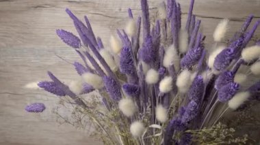 Dried flowers in purple hues rotate close-up. Beautiful lagurus, falyaris and spikelets in a beautiful bouquet. Gift bouquet of dried flowers.