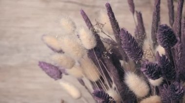 Dried flowers in purple hues rotate close-up. Beautiful lagurus, falyaris and spikelets in a beautiful bouquet. Gift bouquet of dried flowers.