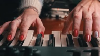 Female hands with fingers play the piano keyboard close-up front view. The piano keys are black and white. Musical instrument, spiritual education, calm music.