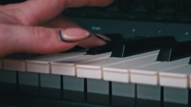Female hands with fingers play the piano keyboard close-up side view. The piano keys are black and white. Musical instrument, spiritual education, calm music.
