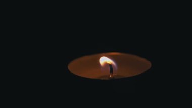 Paraffin candle burns in the dark with a yellow flame. A large fire in a wax candle burns yellow. There is no light in the house, heat from a candle. Poverty, war, a moment of silence.