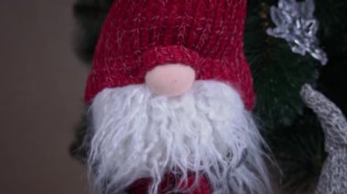 New Years Scandinavian gnome stands near the Christmas tree. A red Christmas elf decorates houses on New Years Eve.