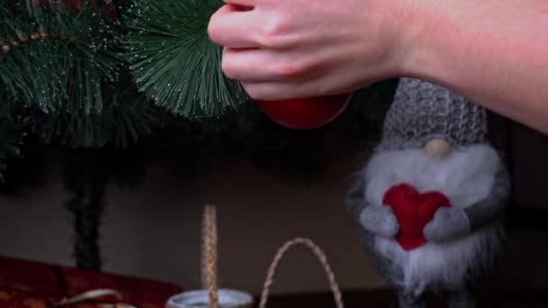 女性の手は緑のクリスマスツリーに新年のおもちゃを掛けます クリスマスツリーの装飾 新年のための家の装飾 — ストック動画