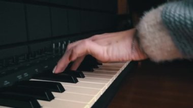 Female hands with fingers play the piano keyboard close-up side view. The piano keys are black and white. Musical instrument, spiritual education, calm music.