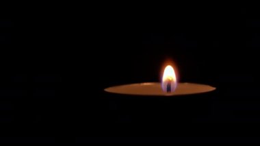 Paraffin candle burns in the dark with a yellow flame. A large fire in a wax candle burns yellow. There is no light in the house, heat from a candle. Poverty, war, a moment of silence.