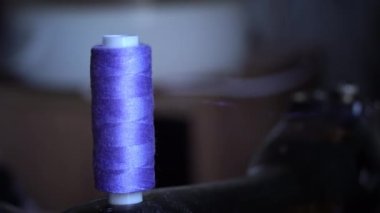 Makaradaki iplik dikiş makinesinde dikiş dikmek için bir bobbin üzerine sarılmış. Terzilik kavramı, kadın hobisi. Modern dikiş işi. Terzi dikiş atölyesinde kumaş dikiyor. Dikiş kumaşı süreci