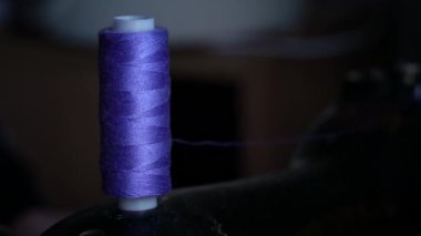 Makaradaki iplik dikiş makinesinde dikiş dikmek için bir bobbin üzerine sarılmış. Terzilik kavramı, kadın hobisi. Modern dikiş işi. Terzi dikiş atölyesinde kumaş dikiyor. Dikiş kumaşı süreci