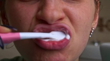Girl brushes her teeth with a brush in the morning close-up. Applying toothpaste to the brush. Morning brushing of teeth. Take care of your teeth. Daily hygiene.