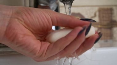 Girl washes her hands with soap under the tap close-up. Hand hygiene from bacteria. Foam lathers in female hands. Soap kills harmful bacteria. Cleanliness.