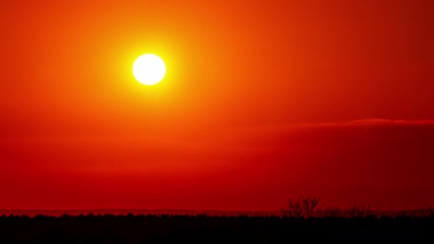 时间流逝 明亮的橙色落日落在云层后面 一天结束时 太阳从地平线下落下 在地平线上方暖空气扭曲的大红色太阳 — 图库视频影像