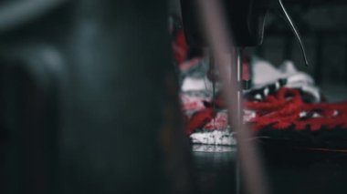 Aged woman sews on an old sewing machine. Needle and foot of sewing machine penetrates fabric with high magnification and super slow motion. Seamstress makes a machine-made even seam on red fabric.