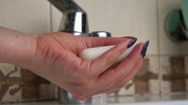 Girl washes her hands with soap under the tap close-up. Hand hygiene from bacteria. Foam lathers in female hands. Soap kills harmful bacteria. Cleanliness.