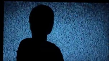 Silhouette of a girl watching TV with noises, shot from the back. Watching TV is a static glitch. Silhouette of a girl watching TV with static noise. Shot behind the shoulders of the model.