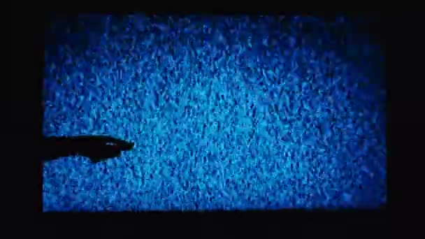 画面上のノイズの背景に 手はテレビのリモコンをオンにします 暗闇でテレビを見ている 爪とテレビ画面上の干渉と手のシルエット — ストック動画
