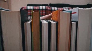 Young girl chooses a book on a shelf with books. Library bookshelves background stack of books. The pages of the book are turning. Reading scientific literature surrounded by books.