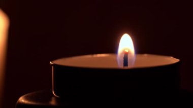 Paraffin candle burns in the dark with a yellow flame. A large fire in a wax candle burns yellow. There is no light in the house, heat from a candle. Poverty, war, a moment of silence.