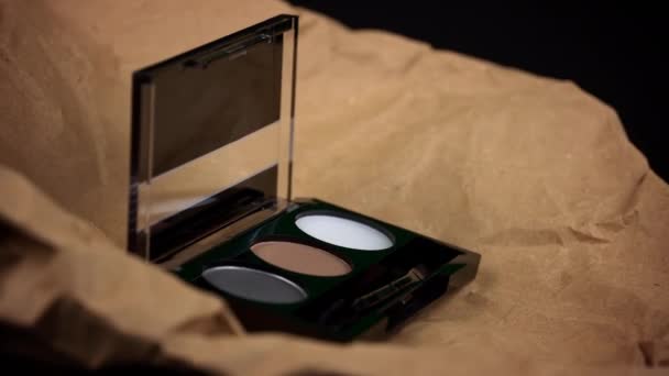 クラフトの背景に眉の影の渦 肉色の新しい原始的な化粧品 化粧パレットセット プロ仕様マルチカラーアイシャドウパレットクローズアップ — ストック動画