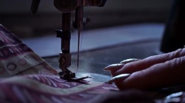 Antika dikiş makinesi iğnesi hareket halinde. Dikiş makinesinin iğnesinin yakın çekimi. Hızla yukarı aşağı hareket ediyor. Bir terzi dikiş atölyesinde kumaş diker. Kumaş dikme süreci.
